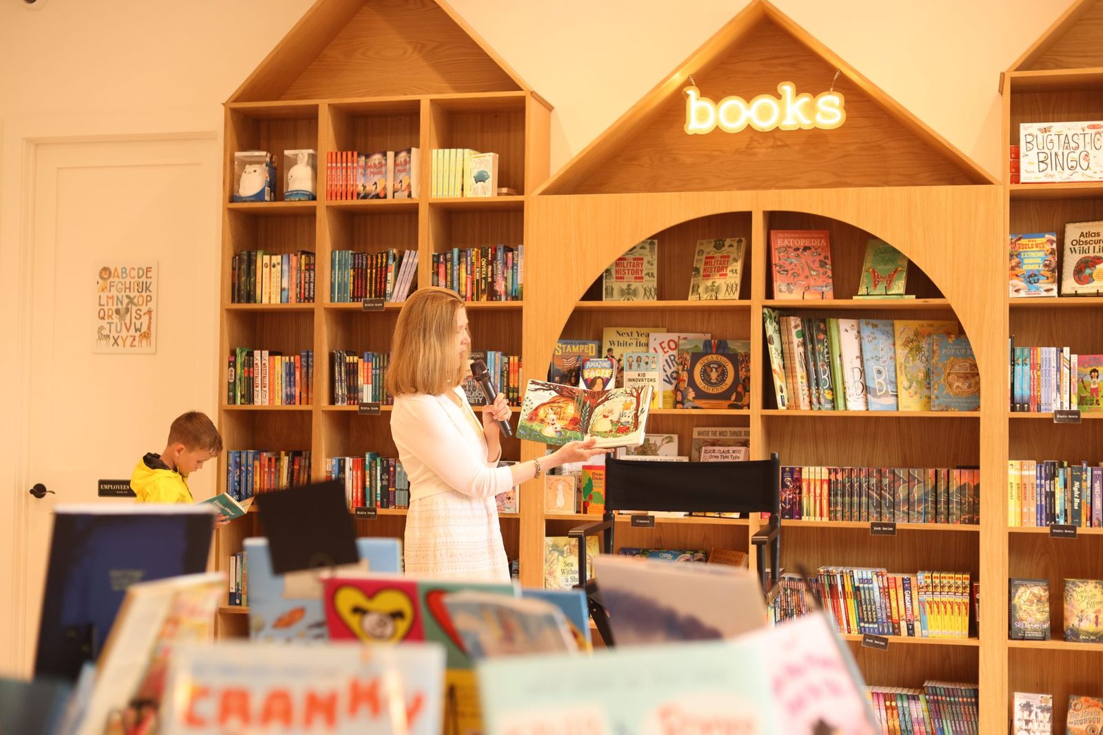 The bookshop owner reading a picture book to a room during an event