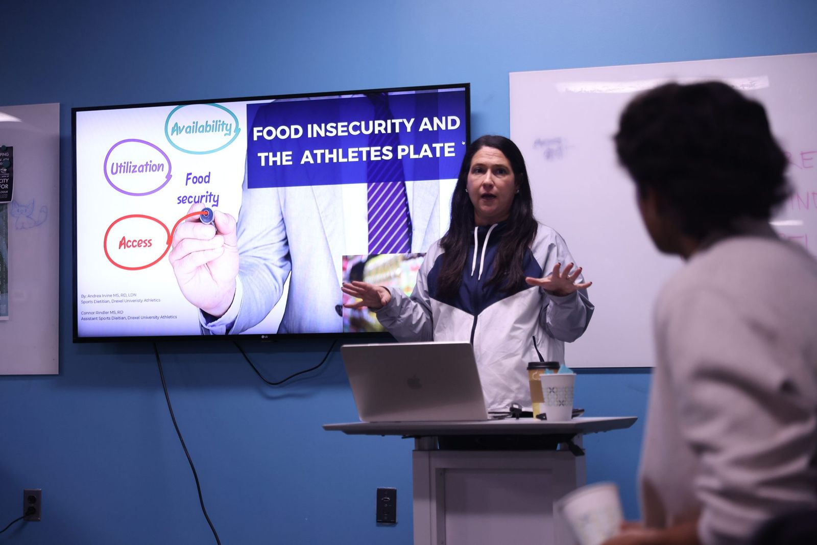 A speaker presenting to a room in front of a screen